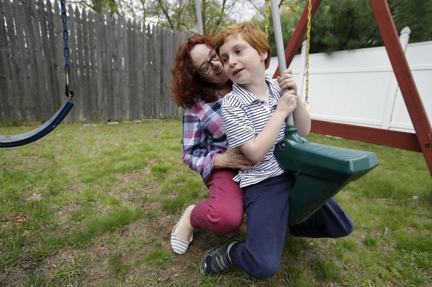 In this Thursday, May 11, 2017 photo Susan Grenon, left, plays with her son Pauly, right, in the backyard of their home, in Smithfield, R.I. Guenon makes sure her son is lathered with sunscreen before he leaves for school in the morning, but the red-headed 10-year-old can't bring a bottle to reapply it without a doctor's note. (AP Photo/Steven Senne)