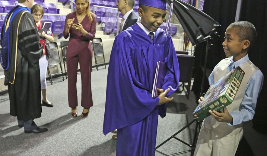 Carson Huey-You, 14, smiles as his 10-year-old brother Cannan shows him one of his graduation gifts, a Hobbit Lego set, after Carson received a bachelor's degree in physics at the Texas Christian University commencement held in Fort Worth, Texas, on Saturday, May 13, 2017. Huey-You, the youngest student ever to attend TCU, also double minored in math and Chinese since enrolling in 2013. (Louis DeLuca/The Dallas Morning News via AP)