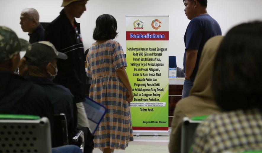 Patients wait near a banner informing about the delay in service put up at the registration desks at Dharmais Cancer Hospital in Jakarta, Indonesia, Monday, May 15, 2017. Dozens of the hospital's computer were hit by the global "ransomware" cyberattack on Saturday causing disruption to services and making patients had to wait longer while staff had to work with paper records. Writings on the banner read: "Currently there is a trouble on the hospital's information system caused by virus. We apologize to patients and visitors for the inconvenience caused. The problem is being resolved at the moment." (AP Photo/Dita Alangkara)
