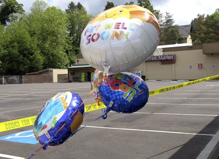 Well-wishing balloons for an injured employee float behind police tape outside a grocery store in Estacada, Ore., Monday, May 15, 2017. Police say a man carrying what appeared to be a human head stabbed an employee at the grocery store. (AP Photo/Gillian Flaccus)