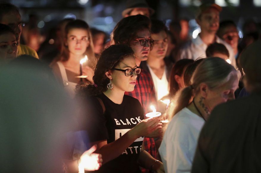 People in support of removal of confederate monuments hold candles during a counter-protest against those on Saturday evening gathered to call on officials to halt the removal of a Gen. Robert E. Lee statue in Charlottesville, Va., Sunday, May 14, 2017. (Ryan M. Kelly/The Daily Progress via AP)