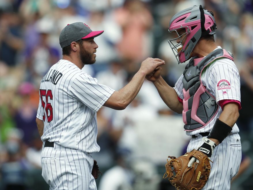 Colorado Rockies relief pitcher Greg Holland, left, is congratulated by catcher Dustin Garneau after retiring Los Angeles Dodgers' Yasiel Puig for the final out in the ninth inning of a baseball game Sunday, May 14, 2017, in Denver. The Rockies won 9-6. (AP Photo/David Zalubowski)
