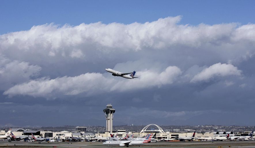 FILE- In this Nov. 27, 2016, file photo, a plane flies over Los Angeles International Airport. A $22 million facility at the airport called the Private Suite opened Monday, May 15, 2017, and offers an exclusive entrance, one-on-one security screening and plush lounges. (AP Photo/John Antczak, File)