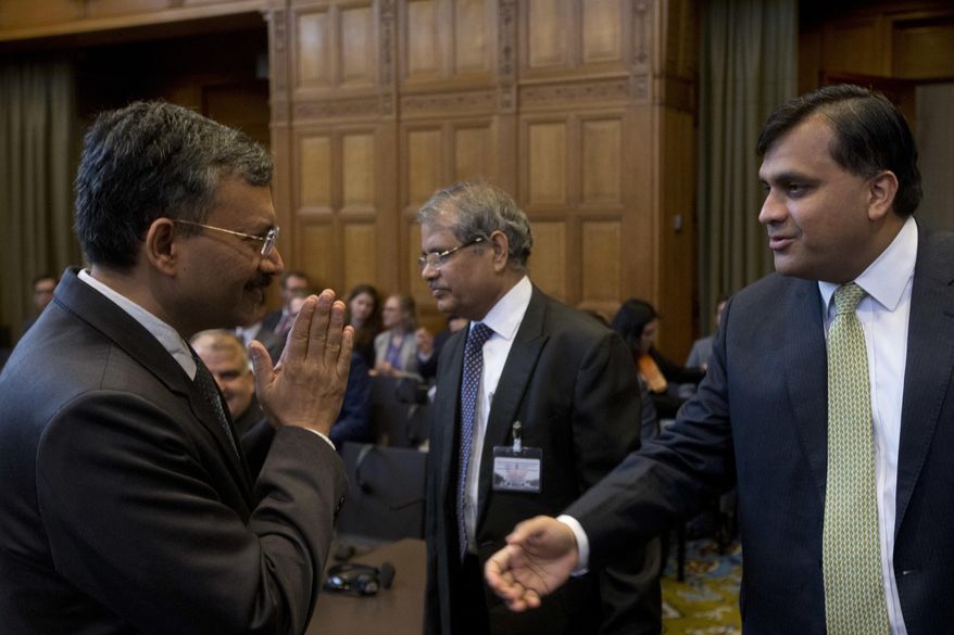 Dr. Deepak Mittal, joint secretary of India's Ministry of External Affairs, left, greets Pakistan's Syed Faraz Hussain Zaidi as they wait for judges to enter the World Court in The Hague, Netherlands, Monday, May 15, 2017. India is taking Pakistan to the United Nations' highest court in an attempt to save the life of an Indian naval officer sentenced to death last month by a Pakistani military court after being convicted of espionage. (AP Photo/Peter Dejong)
