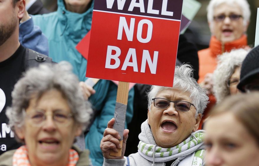 Protesters wave signs and chant during a demonstration against President Donald Trump&#39;s revised travel ban, Monday, May 15, 2017, outside a federal courthouse in Seattle. A three-judge panel of the 9th U.S. Circuit Court of Appeals heard arguments Monday in Seattle over Hawaii&#39;s lawsuit challenging the travel ban, which would suspend the nation&#39;s refugee program and temporarily bar new visas for citizens of Iran, Libya, Somalia, Sudan, Syria and Yemen. (AP Photo/Ted S. Warren)
