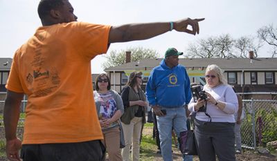 In this April 24, 2017 photo, Yatte Moore, left, farm manager of Blackhawk Courts Farm  and Garden in Rockford, Ill., gives a tour of his garden to founder and CEO of Growing Power, Will Allen, center, Allen, a former professional basketball player founded Growing Power Inc., and is a pioneer of urban agriculture in America. Moore is among those that found inspiration, and has been tending to an urban farm in a public housing complex in southeast Rockford for almost five years. (Kayli Plotner/Rockford Register Star via AP)