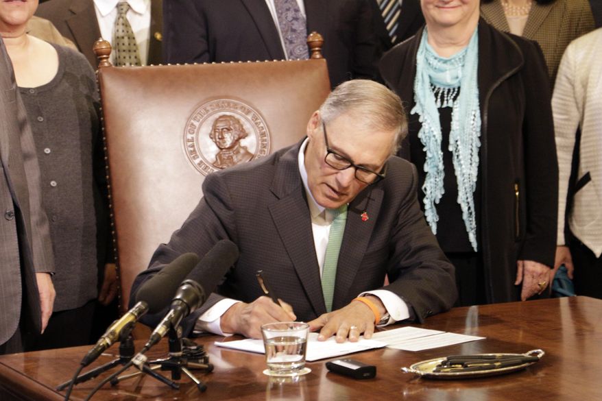 Gov. Jay Inslee signs a bill that seeks to bring Washington state into compliance with the federal REAL ID Act, on Tuesday, May 16, 2017, in Olympia, Wash. Washington state already offers enhanced driver's licenses and IDs that require proof of U.S. citizenship and are already valid under the federal law. The new state law keeps that license and, starting in July 2018, will mark the current standard state licenses to indicate they are not REAL ID compliant. (AP Photo/Rachel La Corte)