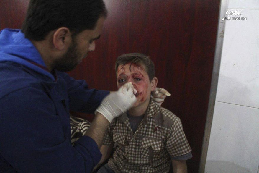 This photo provided by the Syrian anti-government activist group Ghouta Media Center, which has been authenticated based on its contents and other AP reporting, shows a Syrian doctor treating a boy who was wounded by Syrian government forces shelling, at a makeshift hospital in the Hamouriyya neighborhood, an eastern suburb of Damascus, Syria, Tuesday, May 16, 2017. Syrian activists say a number of rockets struck the opposition-controlled suburb, killing several people. (Ghouta Media Center via AP)