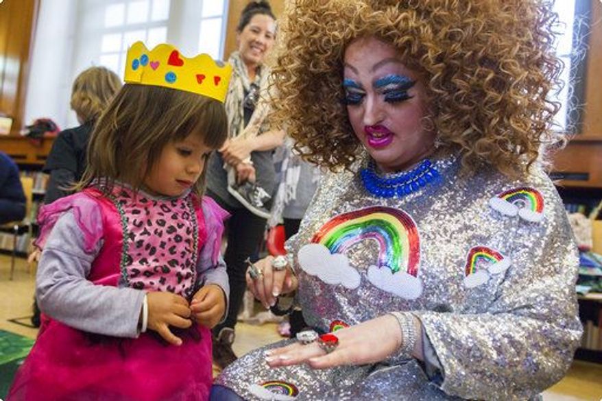 In this Saturday, May 13, 2017 photo, Lil Miss Hot Mess, right, compares outfits with 2-year old Eva McInnes after reading to a group of children during the Feminist Press' presentation of Drag Queen Story Hour at the Park Slope Branch of the Brooklyn Public Library in New York City. (AP Photo/Mary Altaffer)