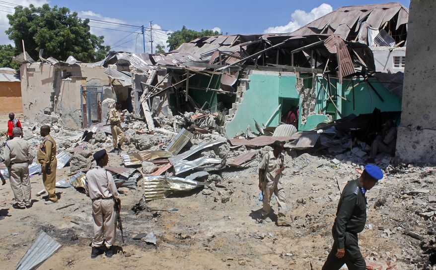 Somali soldiers look at the destroyed houses amidst the wreckage of a car bomb blast in Mogadishu, Somalia Wednesday, May 17, 2017. Three bomb disposal experts were killed as they were trying to dismantle the car laden with explosives, according to police. (AP Photo/Farah Abdi Warsameh)