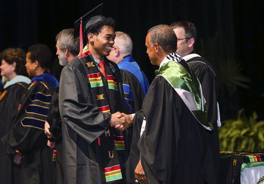 In this April 27, 2017 photo, Maurice Cooley, right, Associate Vice President of Intercultural Affairs at Marshall University, presents Barry Westmoreland with his Kente cloth during Marshall's spring Donning of the Kente ceremony in Huntington, W. Va. Harvard will join a growing number of universities when it holds its first "Black Commencement" on May 23 to recognize the accomplishments of black students and faculty. Organizers said it isn't meant to replace the traditional graduation but to add something that was missing. (Sholten Singer/The Herald-Dispatch via AP)