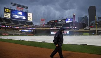 A Target Field security guard walks on field as rain delays the start of a baseball game between the Minnesota Twins and Colorado Rockies on Wednesday, May 17, 2017, in Minneapolis. (AP Photo/Jim Mone)
