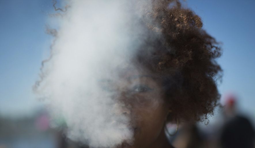 In this April 20, 2016, file photo, a woman exhales after taking a hit from a bong during the annual 4/20 cannabis culture celebration at Sunset Beach in Vancouver, British Columbia. (Darryl Dyck/The Canadian Press via AP, File)