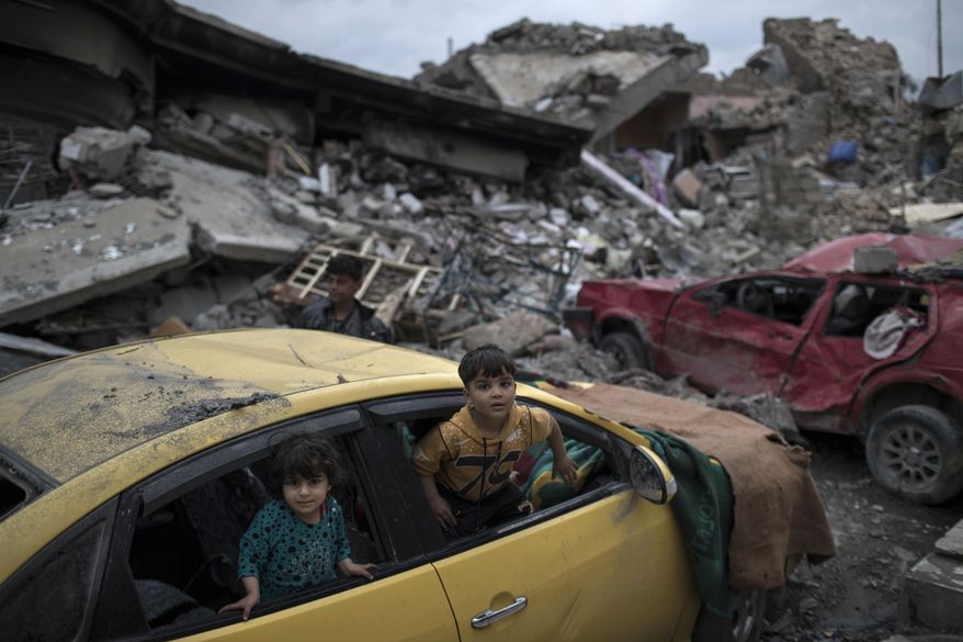 FILE - In this April 1, 2017 file photo, children play inside a damaged car, amid heavy destruction in a neighborhood recently retaken by Iraqi security forces from Islamic State militants on the western side of Mosul, Iraq. Iraq’s Sunni minority is pushing for a greater say in power once the Islamic State group is defeated, reflecting a growing sentiment that the country’s government must be more inclusive to prevent extremism from gaining ground once again. But so far, many Shiite politicians are wary, and the Sunni leadership is divided and disorganized. The danger is that Iraq will fall into the same sectarian cycle that has plagued it for more than a decade. (AP Photo/Felipe Dana, File)