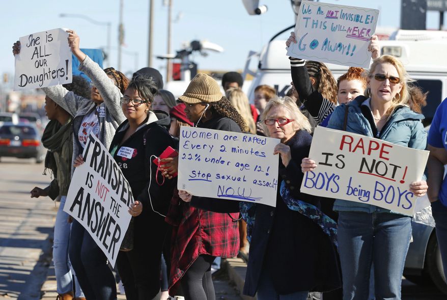 ADVANCE FOR USE MONDAY, MAY 22, 2017 AND THEREAFTER-FILE - In this Nov. 24, 2014 file photo, students, parents and grandparents hold signs during a protest across the street from Norman High School in Norman, Okla. Three girls said that after they reported being assaulted, they were harassed by other students and had to leave Norman High School because officials did nothing to stop the bullying, according to a lawsuit they settled with the district. The district said it investigated, quickly suspended the boy accused and responded to one bullying case. The boy pleaded no contest to rape charges in one incident and served time. (AP Photo/Sue Ogrocki, File)