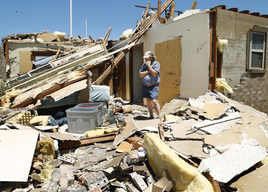 Jody Darling, a friend of the residents of this home in Elk City, Okla., talks on a phone while standing in a room of the house that is now totally exposed on Wednesday, May 17, 2017. Over a dozen tornadoes were reportedly spawned by powerful storms that raced through a swath of the central U.S. stretching from Texas to the Great Lakes on Tuesday evening. (Jim Beckel/The Oklahoman via AP)