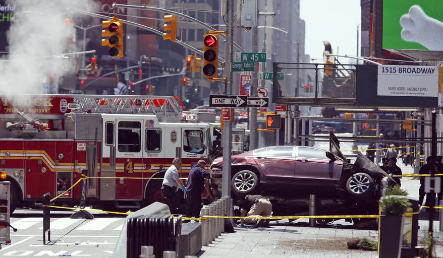 Investigators look under a smashed car that sits on the corner of Broadway and 45th Street in New York's Times Square after ploughing through a crowd of pedestrians at lunchtime on Thursday, May 18, 2017. Police do not suspect a link to terrorism and the driver was taken into custody to be tested for alcohol. (AP Photo/Seth Wenig)