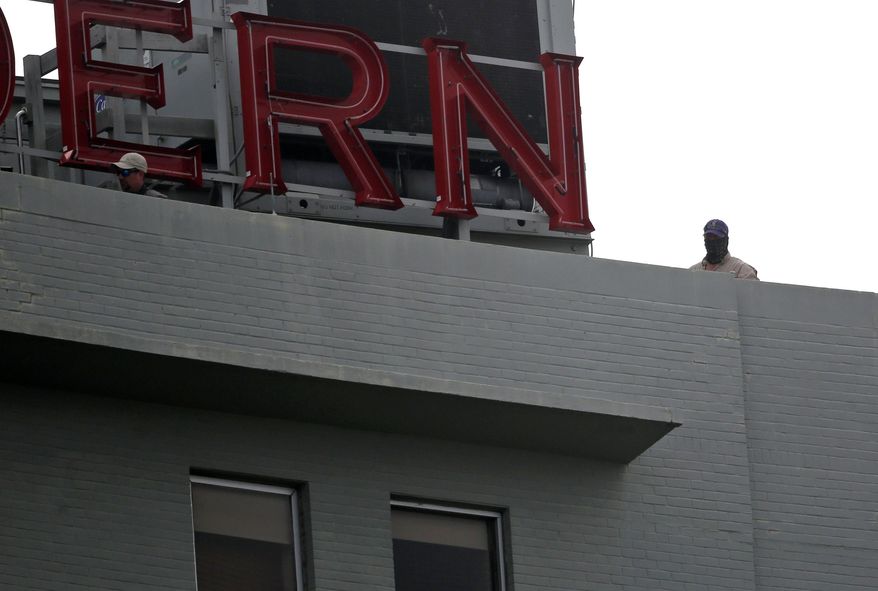 Security personnel wearing a mask stands atop a hotel in Lee Circle as workers prepare to take down the statue of Gen. Robert E. Lee, who commanded Confederate armies fighting the United States in the Civil War, Friday, May 19, 2017, in New Orleans. (AP Photo/Gerald Herbert)