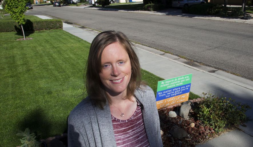 In this May 10, 2017, photo Lauresta Welty poses for a photo next to a sign in front of her home in Boise, Idaho. "We want to spread love and hope to each other, our neighbors, and to everyone," said Welty. (Darin Oswald/Idaho Statesman via AP)