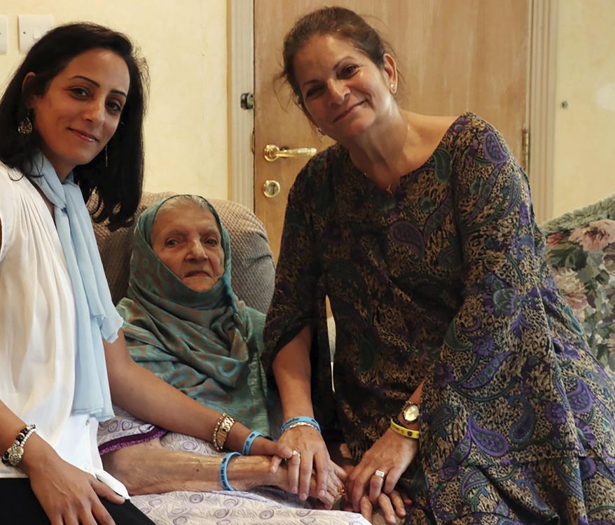 In this undated photo provided by Sahar Nasief, Nassief, right, poses with her mother Naila Mohammed Saleh Nasief, center, and daughter Lubna Jamjoom, while wearing blue wrist bands that say in Arabic, "I am my own guardian," In Jiddah, Saudi Arabia. The three generations of Saudi women have lived their lives under restrictive male guardianship laws that they say should be changed to give women more control of their lives. (Sahar Nasief via AP)