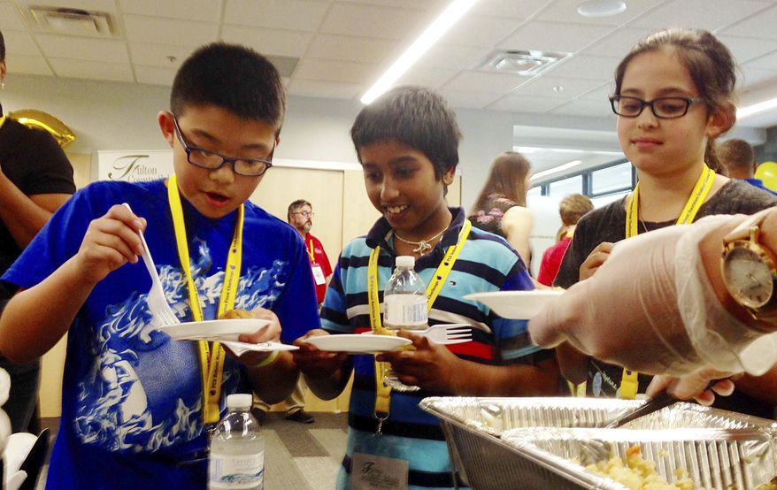 In this May 18, 2017 photo, Eric Zheng, left, Rohith Pallamreddy and Sophia Ullman, right, sample a Korean BBQ chicken meal at the Fulton County Schools Administrative Center, in Atlanta. The 4th graders participated in a taste test event that school district officials started last year to promote healthier menu items that stick to federal regulations under review by the Trump administration. (AP Photo/ Kathleen Foody)