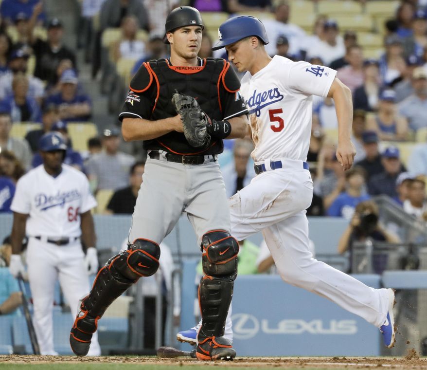 Los Angeles Dodgers' Corey Seager, right, scores past Miami Marlins catcher J.T. Realmuto on a ball hit by Austin Barnes during first inning of a baseball game in Los Angeles, Friday, May 19, 2017. (AP Photo/Chris Carlson)