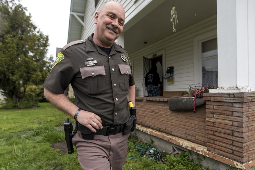 In this Thursday, May 11, 2017 photo, Deputy Kevin Dickey, of the Lewis County Sheriff's Office, leaves a house in Centralia, Wash., after checking in on a drug court participant. Deputy Dickey spends his days randomly checking in on drug court participants. Lewis County is one of 24 counties in the state that have adult drug courts. (Pete Caster/The Chronicle via AP)