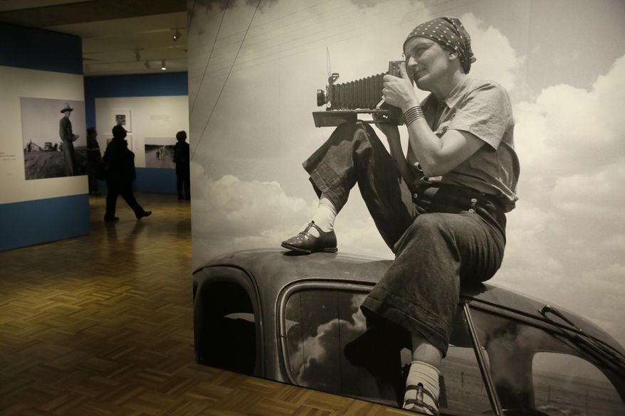 In this photo taken Thursday, May 11, 2017, is a 1935 image of Dorothea Lange atop a car in Texas on the plains that is in the exhibit "Dorothea Lange: Politics of Seeing," at the Oakland Museum of California in Oakland, Calif. The three major themes of the Lange display are the Great Depression, the home front during World War II and the urban decline and postwar sprawl in California. Running through August 13, the exhibit includes 100 of Lange's photographs, including recognized works as well as new, improved unframed prints that have been digitally scanned. (AP Photo/Eric Risberg)