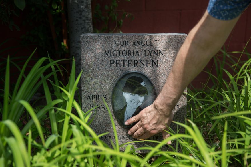 In this May 9, 2017 photo, Sal Rubino, owner of The Cafe in Paristown Pointe, Ky, brushes away grass from a memorial for a former employee who overdosed while he was on vacation. The Café is likely one of a few restaurants in the area that don't sell alcohol. It's a decision the Rubinos originally made for their own benefit, but it's since turned their restaurant into somewhat of a "safe haven" for recovering addicts working in the industry. (Liz Moughon /The Courier-Journal via AP)