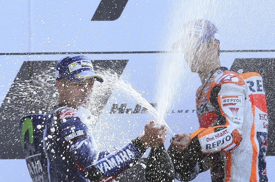 MotoGP rider Maverick Vinales of Spain, left, sprays sparkling wine with third placed Dani Pedrosa of Spain, right, as he celebrates on the podium after wining the French Grand Prix's race, in Le Mans, western France, Sunday, May 21, 2017. (AP Photo/David Vincent)