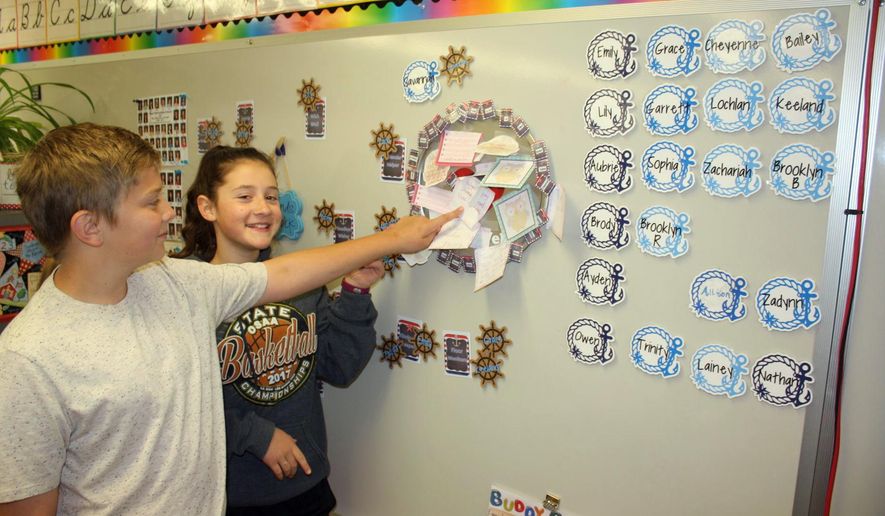 This photo taken May 11, 2017, shows Keeland Walker and Brooklyn Bailey posting a good wish at the Wishing Well for someone in the class as part of the Conscious Discipline program that is a part of the daily routine in Shannon's Grauf's fifth-grade classroom at West Intermediate School in Sutherlin, Ore. Grauf’s fifth-grade class is just one of the classes in Sutherlin that uses a program called Conscious Discipline Building Resilient Children. Exercises and music are used to get students focused and excited about the day. (Dan Bain/The News-Review via AP)