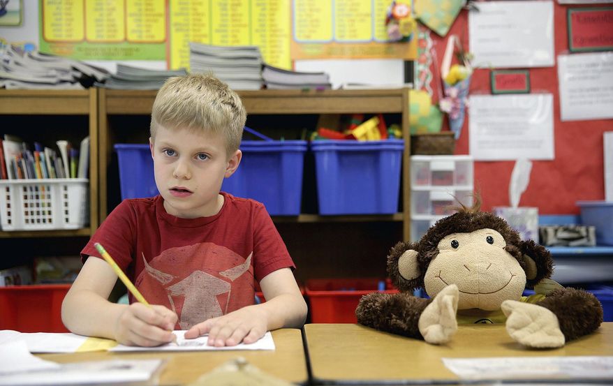 In this Thursday, May 4, 2017 photo, Richard Gordon Elementary School second grade student Dane Menge, 8, thinks about what he is going to write in a letter to student Makoa Saffery who is suffering from cancer in Kingston, Wash.. The monkey in the chair next to him is where Saffery sits in class. Thursday, May 4, 2017 in Kingston Wash (Larry Steagall/Kitsap Sun via AP)