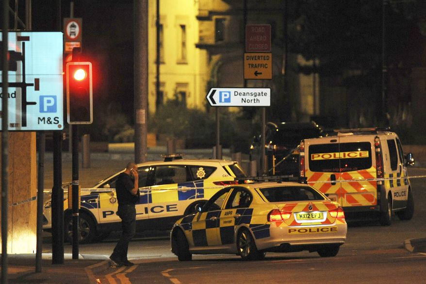Armed police block a road near to the Manchester Arena in central Manchester, England, Tuesday, May 23, 2017. An explosion struck an Ariana Grande concert in northern England late Monday, killing over a dozen people and injuring dozens in what police say they are treating as a terrorist attack. (AP Photo/Rui Vieira)