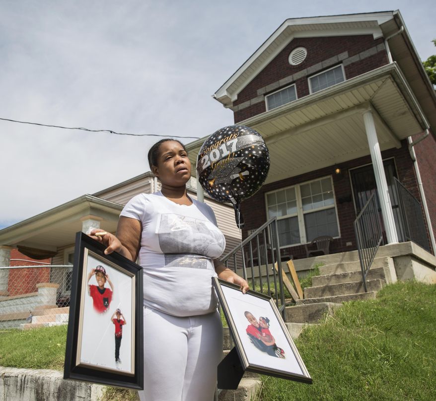 Micheshia Norment holds photos of her son, Dequante Hobbs Jr., 7, Monday, May 22, 2017, who was shot Sunday night by a stray bullet through the window of his Louisville, Ky., home while he was eating a snack at the dinner table. He was supposed to graduate kindergarten on Tuesday. Police are still searching for information on his death. (Liz Moughon/The Courier-Journal via AP)