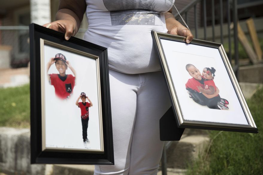 Micheshia Norment holds photos of her son, Dequante Hobbs Jr., 7, Monday, May 22, 2017, who was shot Sunday night by a stray bullet through the window of his Louisville home while he was eating a snack at the dinner table. He was supposed to graduate kindergarten on Tuesday. Police are still searching for information on his death. (Liz Moughon/The Courier-Journal via AP)