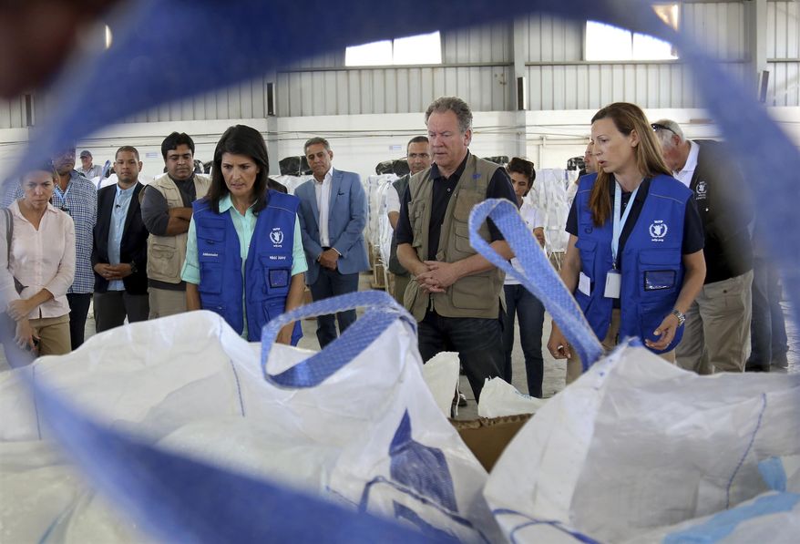 U.S. Ambassador to the United Nations Nikki Haley, center left, and World Food Program director David Beasely, center inspects a food pallet to be air-dropped deep inside Syria, in Amman, Jordan, Sunday, May 21, 2017. Haley said the Trump administration wants to step up help for the millions of displaced Syrians. Yet Nikki Haley's message is at odds with President Donald Trump's "America First" agenda, his planned budget cuts and his hardline position on admitting refugees. (AP Photo/Raad Adayleh, Pool)