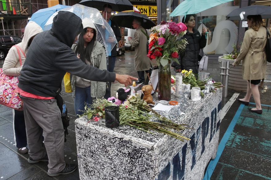 People in New York's Times Square, Monday May 22, 2017, visit a concrete block that has become a makeshift memorial to those injured by a man who steered his car onto a sidewalk and into pedestrians for three blocks before crashing. Thomas Elsman, the father of 18-year-old Alyssa Elsman who was killed killed by the out-of-control driver, left a note Saturday, top center, that said there were "no words that can express our gratitude" for the support. (AP Photo/Richard Drew)