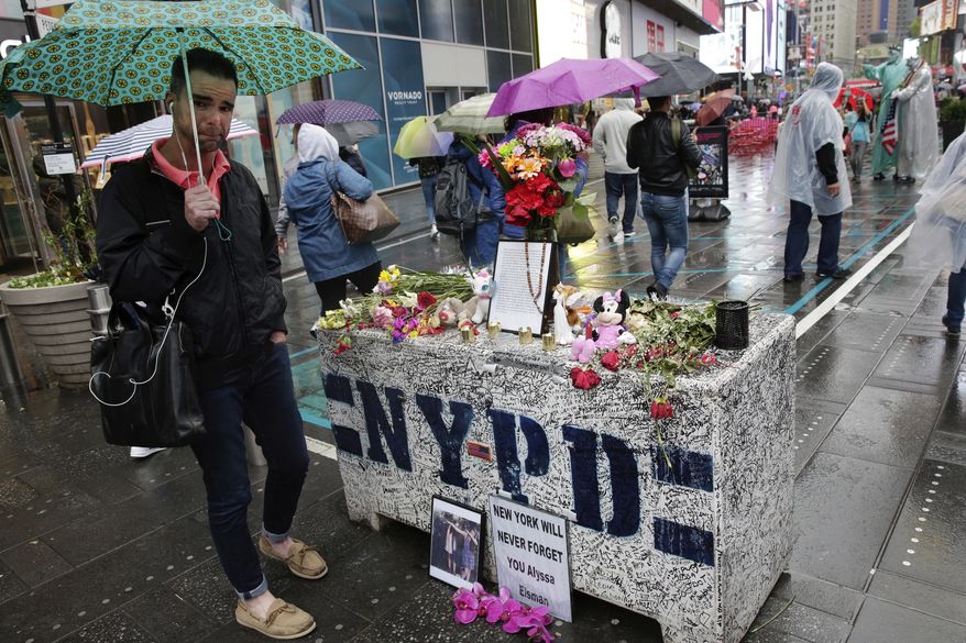 People in New York's Times Square, Monday, May 22, 2017, visit a concrete block that has become a makeshift memorial to those injured by a man who steered his car onto a sidewalk and into pedestrians for three blocks before crashing. Thomas Elsman, the father of 18-year-old Alyssa Elsman who was killed killed by the out-of-control driver, left a note Saturday, top center, that said there were "no words that can express our gratitude" for the support. (AP Photo/Richard Drew)