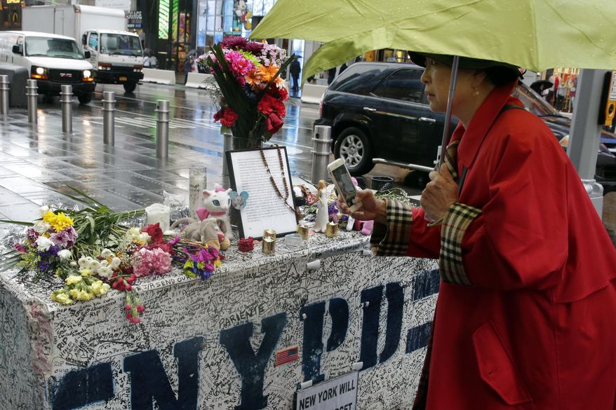 People in New York's Times Square, Monday May 22, 2017, visit a concrete block that has become a makeshift memorial to those injured by a man who steered his car onto a sidewalk and into pedestrians for three blocks before crashing. Thomas Elsman, the father of 18-year-old Alyssa Elsman who was killed killed by the out-of-control driver, left a note Saturday, top center, that said there were "no words that can express our gratitude" for the support. (AP Photo/Richard Drew)