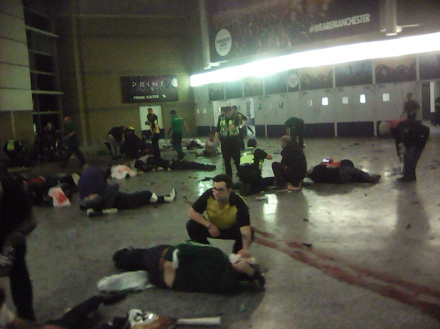 Helpers attend to injured people inside the Manchester Arena, Manchester, Britain, after a blast Monday, May 22, 2017. An apparent suicide bomber attacked an Ariana Grande concert as it ended Monday night, killing over a dozen of people among a panicked crowd of young concertgoers. (PA via AP)