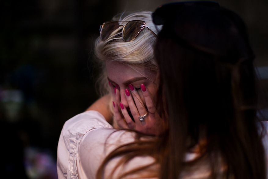 People cry after a vigil in Albert Square, Manchester, England, Tuesday May 23, 2017, the day after the suicide attack at an Ariana Grande concert that left 22 people dead as it ended on Monday night. (AP Photo/Emilio Morenatti)