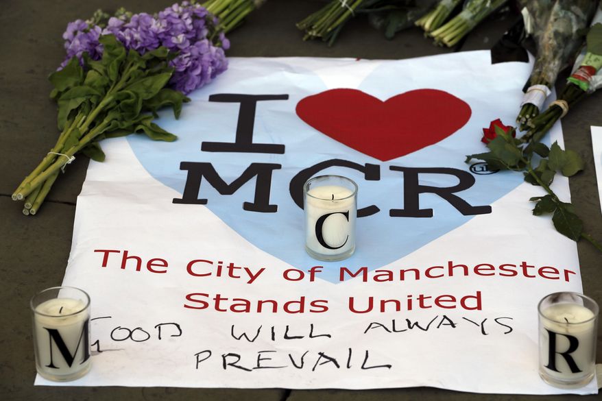 A sign is seen with flowers and candles after a vigil in Albert Square, Manchester, England, Tuesday May 23, 2017, the day after the suicide attack at an Ariana Grande concert that left 22 people dead as it ended on Monday night. (AP Photo/Kirsty Wigglesworth)