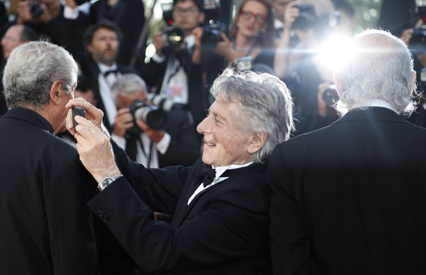 Director Roman Polanski, centre, takes photographs as poses with former Palme d'or winners for photographers upon arrival at the 70th Anniversary of the film festival, Cannes, southern France, Tuesday, May 23, 2017. (AP Photo/Thibault Camus)