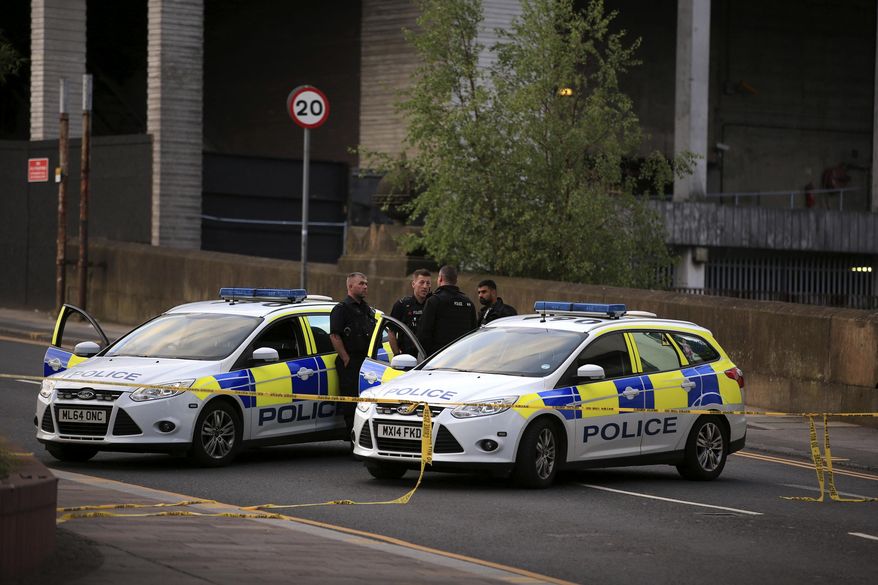 Police officers stand next to their vehicles near the Manchester Arena after a blast at Ariana Grande concert Tuesday May 23, 2017. An explosion struck the concert attended by thousands of young music fans in northern England, killing more than a dozen of people and injuring dozens in what police said Tuesday was being treated as a terrorist attack. (Peter Byrne/PA via AP)