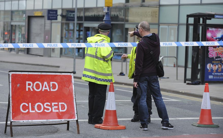 Police block a road near to the Manchester Arena in central Manchester, England Tuesday, May 23, 2017. An explosion struck an Ariana Grande concert attended by thousands of young music fans in northern England late Monday, killing over a dozen people and injuring dozens in what police said Tuesday was being treated as a terrorist attack. (AP Photo/Rui Vieira)