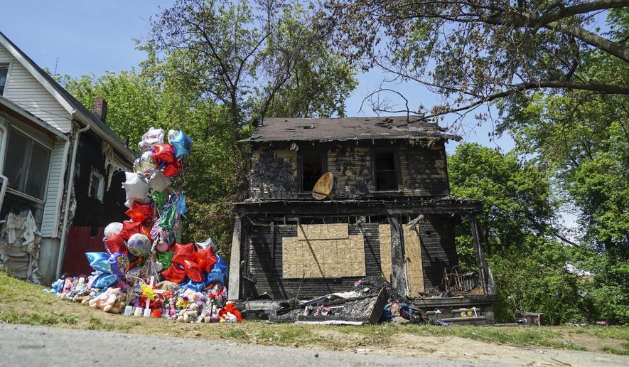 A balloon memorial sits outside the burnt home of a family that died in a fire in Akron, Ohio on Tuesday, May 23, 2017. Officials have arrested a man suspected of intentionally setting the fire. (AP Photo/Dake Kang)
