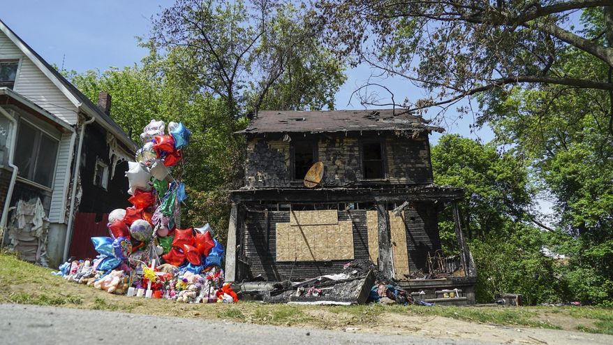 A balloon memorial sits outside the burnt home of a family that died in a fire in Akron, Ohio on Tuesday, May 23, 2017. Officials have arrested a man suspected of intentionally setting the fire. (AP Photo/Dake Kang)