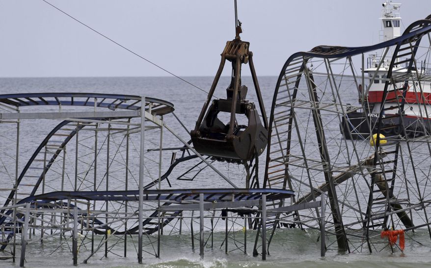 FILE – In this May 14, 2013, file photo, the claw of a crane, center, tears through the structure of the Jet Star roller coaster, partially submerged in the Atlantic Ocean after Superstorm Sandy destroyed part of the Casino Pier, as workers begin demolishing the roller coaster in Seaside Heights, N.J. A new roller coaster named Hydrus, built safely inland above the beach rather than out over the water more than four years after the storm caused billions of dollars' worth of damage to the coast. (AP Photo/Julio Cortez, File)