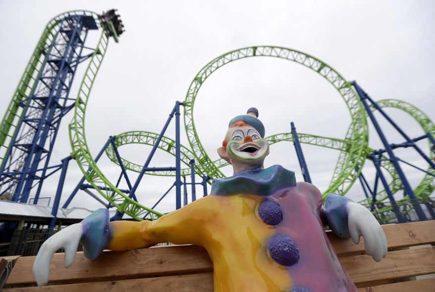 In this May 20, 2017, photo, a statue of a clown rests on a bench as people riding the Hydrus roller coaster go over a drop at Casino Pier in Seaside Heights, N.J. More than four years after Superstorm Sandy destroyed part of the Casino Pier and left the since-demolished Jet Star roller coaster partially submerged in the Atlantic Ocean, the new roller coaster named Hydrus opened May 6, 2017, built safely inland above the beach rather than out over the water. (AP Photo/Julio Cortez)