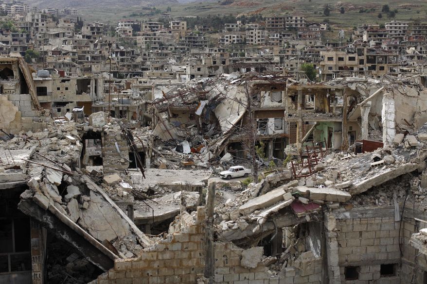In this May 18, 2017 photo, a car passes by damaged streets at the mountain resort town of Zabadani in the Damascus countryside, Syria. Once a popular summer resort famed for its fruit trees and favored by tourists from rich Gulf Arab countries, the Damascus suburb town of Zabadani is now a deserted, endless vista of pulverized buildings after thousands of rebels were driven out along with the town’s original inhabitants. (AP Photo/Hassan Ammar)